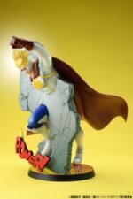 Vue 3/4 de face à mi-distance de la figurine de Mirio Togata de My Hero Academia en costume de héros moderne, avec un mur fissuré en fond.