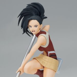 Vue 3/4 de face à mi-distance de la figurine de Momo Yaoyorozu de My Hero Academia en haut sans manches rouge et jupe beige, tenant un bâton.