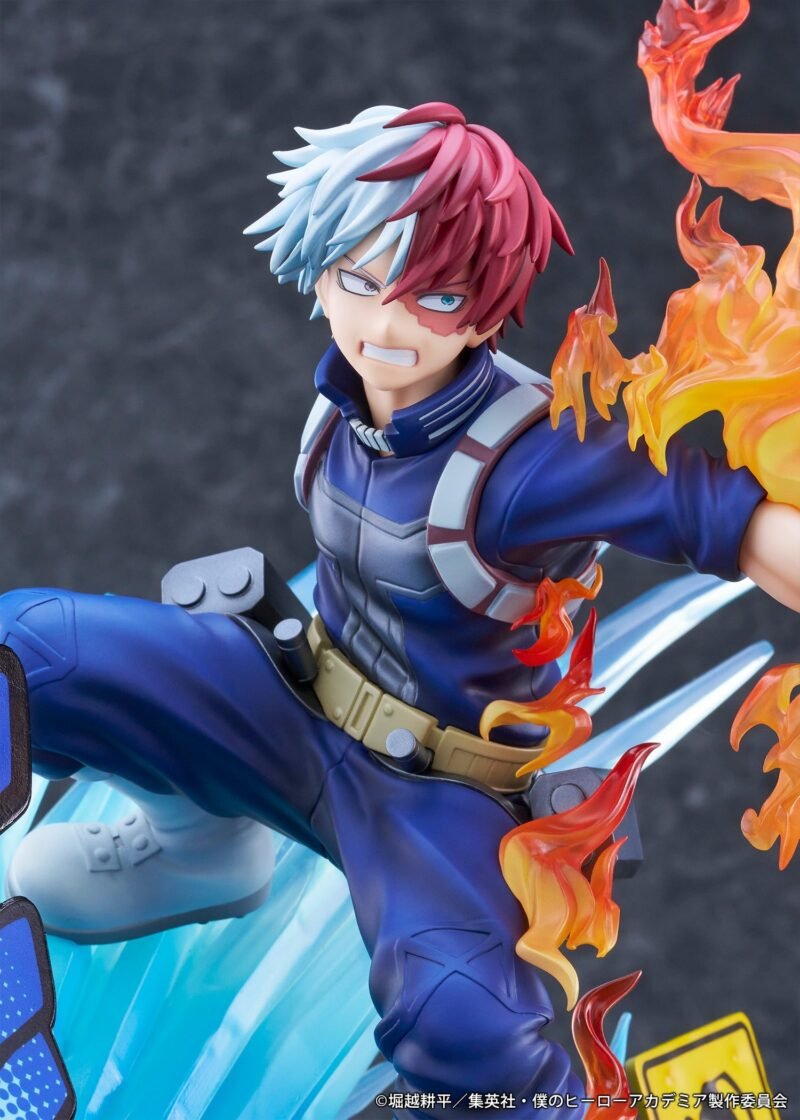 my-hero-academia-figurine-shoto-todoroki-short-ver_18 Vue 3/4 de face à mi-distance de la figurine de Shoto Todoroki de My Hero Academia en costume de héros bleu, avec des flammes émanant du côté gauche.