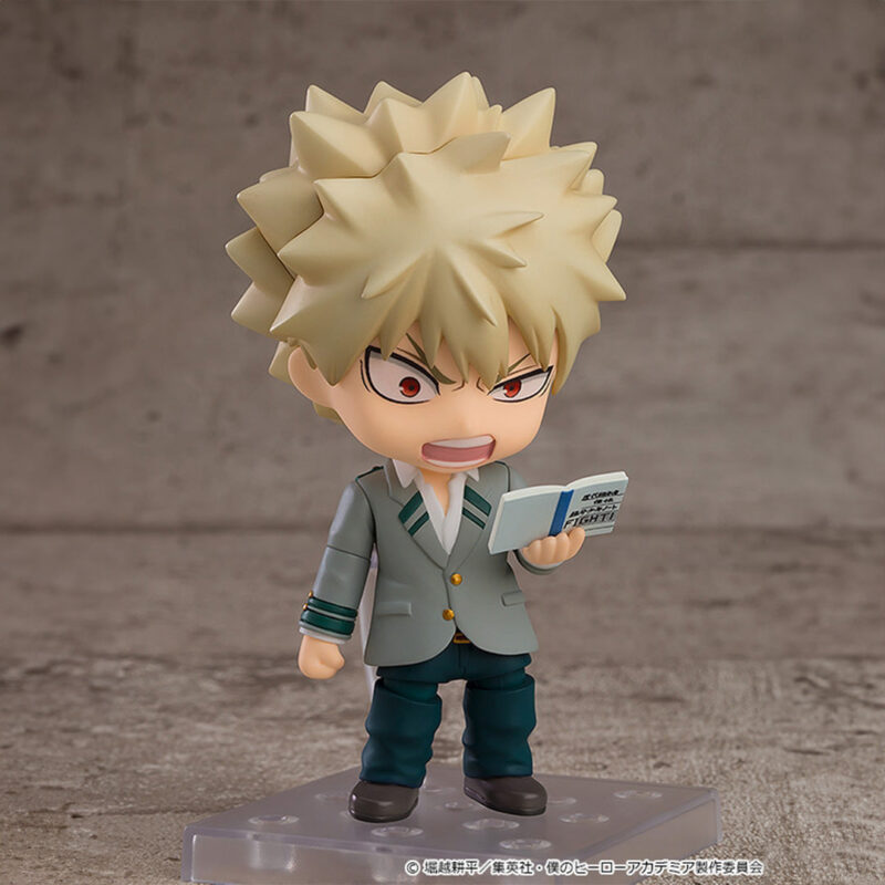 Vue 3/4 de face à mi-distance de la figurine Nendoroid de Katsuki Bakugo de My Hero Academia en uniforme scolaire, tenant un livre.