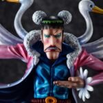 Figurine de Bon Clay avec une pose dynamique, portant une jupe bleue rayée, une ceinture rouge et une longue cape rose ornée d'ailes et de têtes de cygne, fabriquée par MEGAHOUSE.