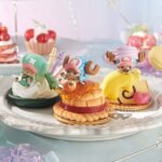 Figurine de Tony Tony Chopper allongé sur une pâtisserie avec un coulis jaune, présentant des détails minutieux inspirés de l'univers de One Piece, incluant un motif tourbillonnant et un symbole d'amour sur l'assiette.
