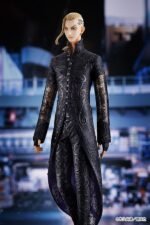 Vue 3/4 de face à mi-distance de la figurine de Ken Ryuguji (Draken) de Tokyo Revengers en long manteau noir, avec un tatouage visible.